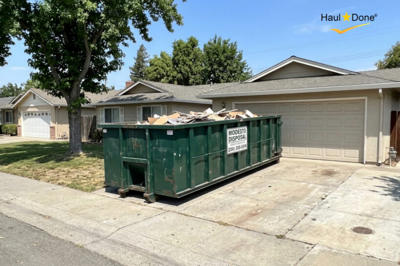 A large roll-off dumpster placed on a residential driveway in Modesto
